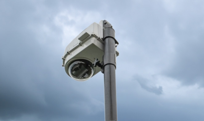 D2-BASE-EXT-Gehäuse mit PTZ-Kamera an einem Mast im Außenbereich